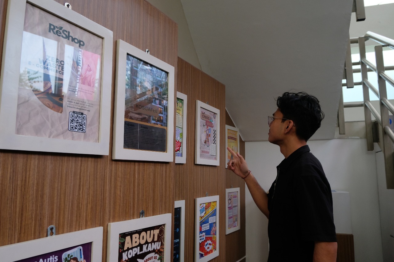 Salah satu mahasiswa melihat poster pameran hasil tugas akhir mahasiswa Prodi Inovasi Digital ITS di ruang pamer CCWS Inovasi Digital ITS