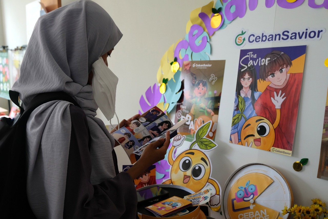 Salah satu warga pengunjung pameran saat membaca komik edukasi perencanaan keuangan karya mahasiswa Departemen DKV ITS