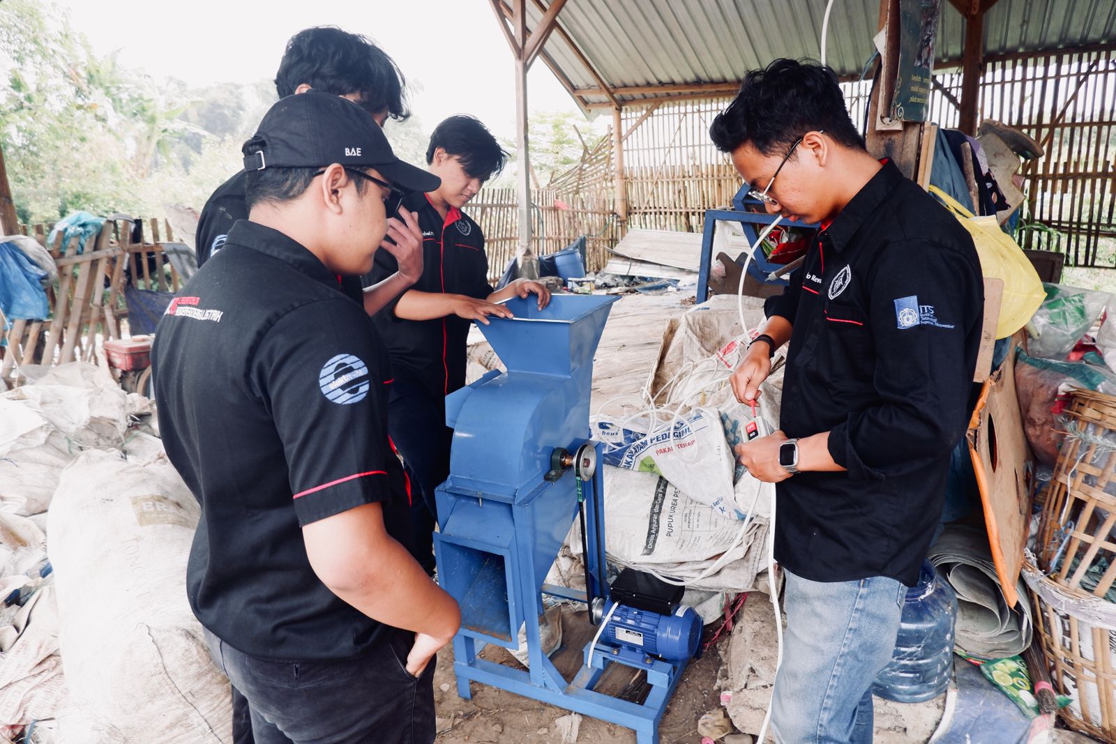 Mahasiswa KKN tengah mendemostrasikan mesin pencacah sampah yang telah tersambung dengan sistem on-grid photovoltaik