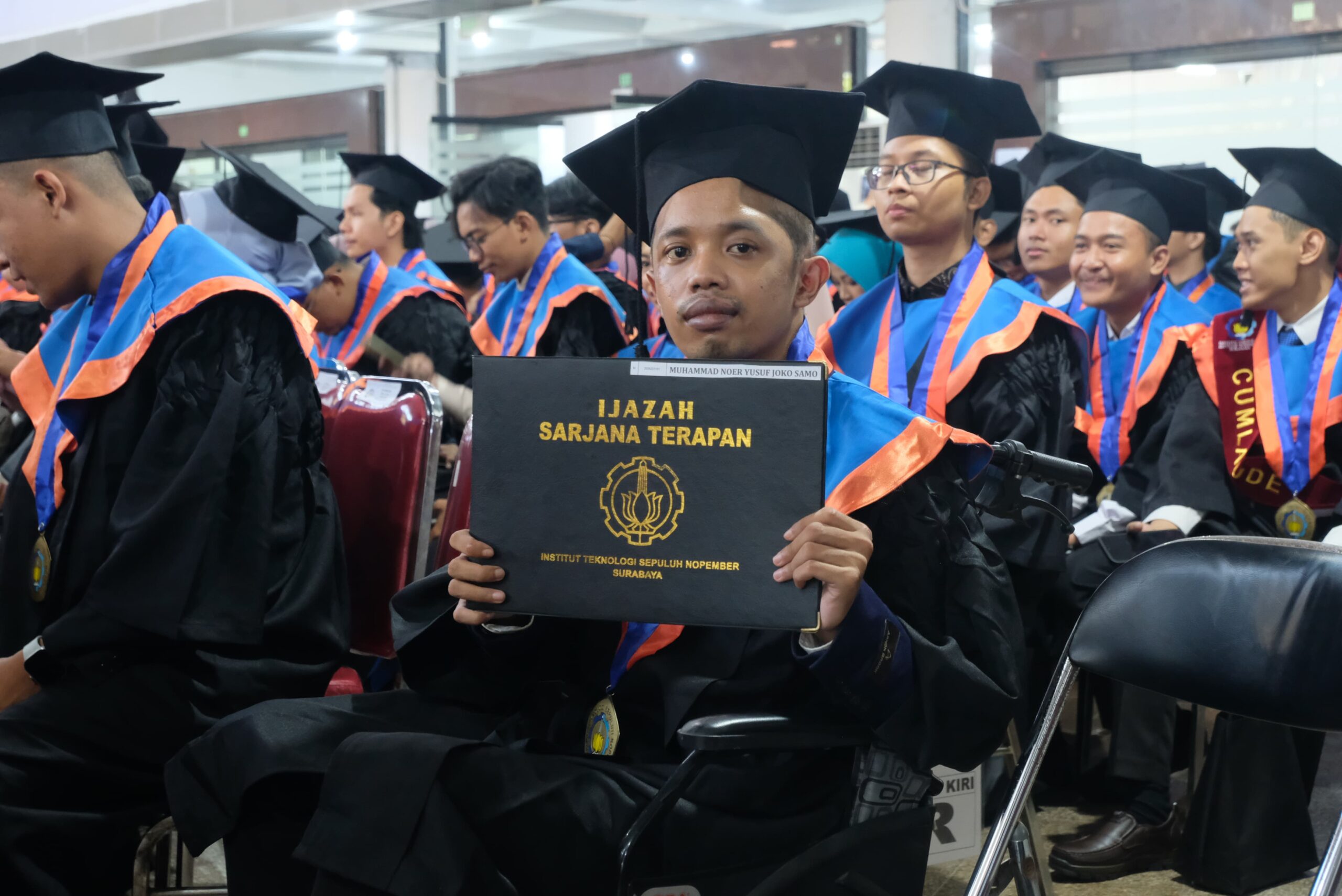 Gambar wisudawan menggunakan kursi roda pada prosesi wisuda