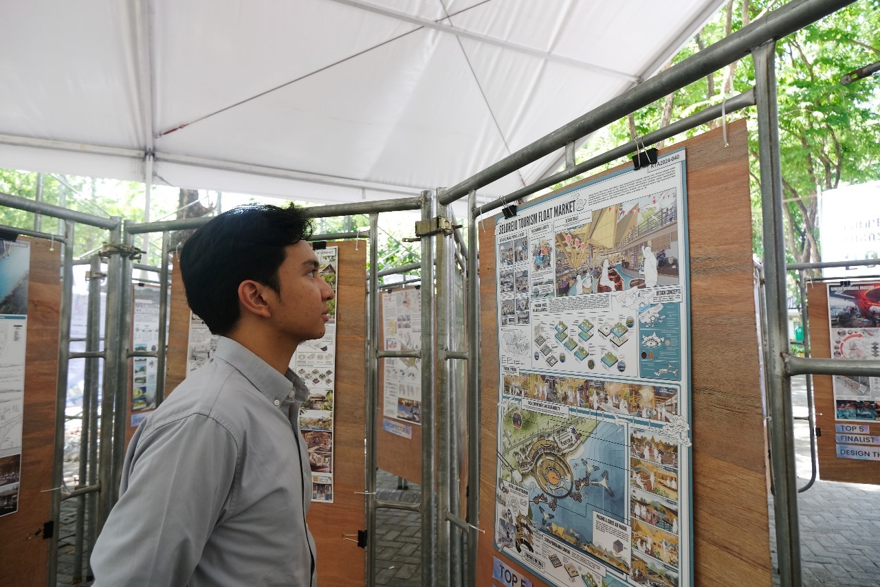 Salah satu pengunjung pameran mengamati inovasi dari finalis kategori Architectural Contribution pada Pameran Kompetisi Tugas Akhir (KTA) 2024 di ITS